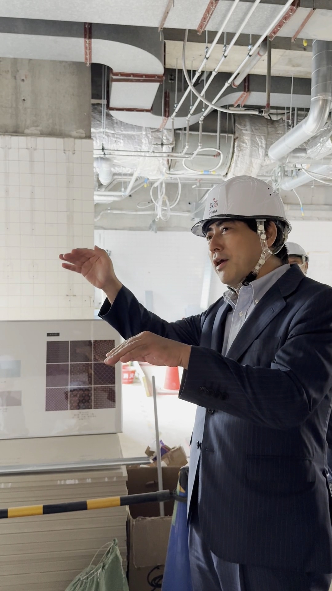 建設中の現場でヘルメットを着用し施工内容を説明するサウナ王 太田 広